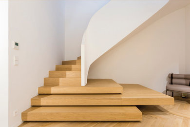 Cette image montre un escalier courbe minimaliste avec des marches en bois, des contremarches en bois et un garde-corps en matériaux mixtes.
