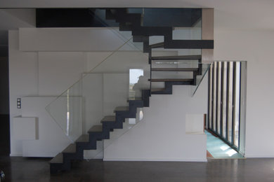 Imagen de escalera actual sin contrahuella con escalones de mármol y barandilla de vidrio