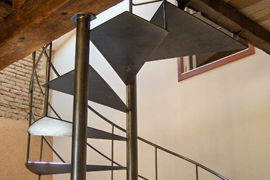 Cette image montre un escalier avec des marches en métal et un garde-corps en métal.