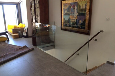 Esempio di una scala a "L" moderna di medie dimensioni con pedata in vetro e alzata in metallo