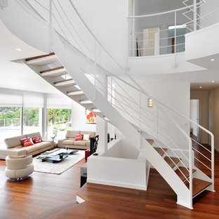 Réalisation d'un grand escalier sans contremarche courbe minimaliste avec des marches en bois.