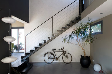 Cette image montre un escalier droit design avec des marches en métal, des contremarches en métal, un garde-corps en câble et éclairage.