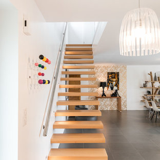 Inspiration pour un grand escalier sans contremarche droit design avec des marches en bois et un garde-corps en métal.