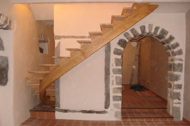 Aménagement d'un grand escalier courbe campagne avec des marches en bois.