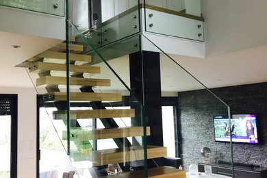 Cette photo montre un escalier sans contremarche droit tendance avec des marches en bois et un garde-corps en verre.