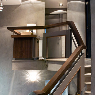 Foto di una grande scala curva minimal con pedata in travertino, alzata in travertino e parapetto in legno