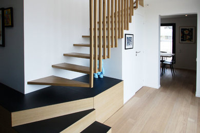 Idées déco pour un grand escalier sans contremarche courbe contemporain avec des marches en bois et un garde-corps en bois.