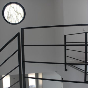 Immagine di una grande scala curva contemporanea con pedata in pietra calcarea, alzata in pietra calcarea e parapetto in metallo
