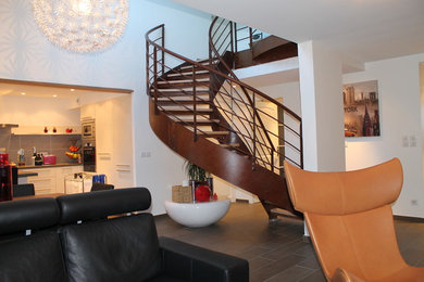 Ejemplo de escalera de caracol actual de tamaño medio sin contrahuella con escalones de madera y barandilla de metal