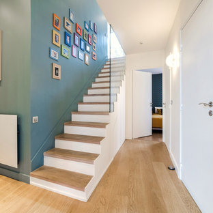 Inspiration pour un escalier droit nordique avec des marches en bois, des contremarches en béton et un garde-corps en verre.