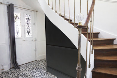 Cette photo montre un grand escalier courbe avec des marches en bois, des contremarches en bois, un garde-corps en métal et boiseries.