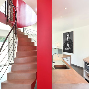 Réalisation d'un grand escalier courbe design avec des marches en béton et des contremarches en béton.