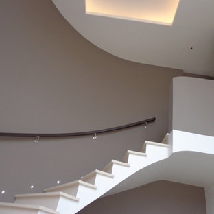 Immagine di una scala curva minimal di medie dimensioni con pedata in pietra calcarea e parapetto in legno