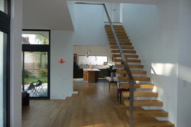 Diseño de escalera recta minimalista grande con escalones de madera y barandilla de metal