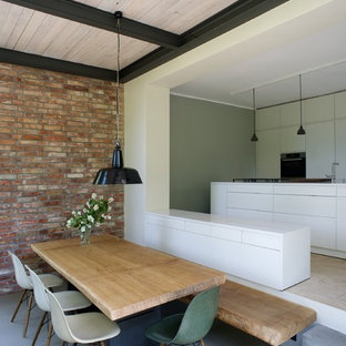 Inspiration pour une salle à manger ouverte sur la cuisine design de taille moyenne avec un mur rouge, béton au sol et aucune cheminée.