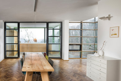 Mittelgroße Nordische Wohnküche mit weißer Wandfarbe, hellem Holzboden, Kaminofen und braunem Boden in Sonstige