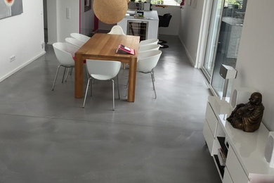 Ejemplo de comedor moderno grande abierto con paredes blancas, suelo de cemento y suelo gris