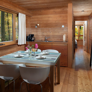 Kleine Urige Wohnküche mit brauner Wandfarbe, braunem Holzboden, braunem Boden und Holzwänden in Bremen