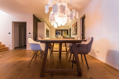 Geräumige Moderne Wohnküche mit weißer Wandfarbe, hellem Holzboden und braunem Boden in Dortmund