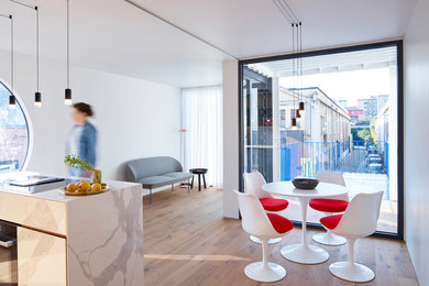 Kleine Moderne Wohnküche ohne Kamin mit weißer Wandfarbe, braunem Holzboden und braunem Boden in Stuttgart