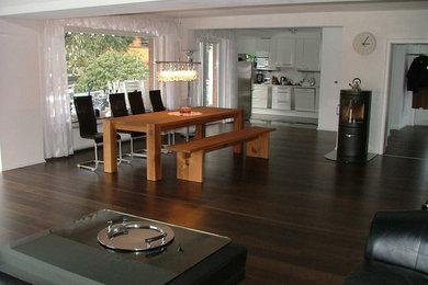 Photo of a large contemporary open plan dining room in Other with white walls, dark hardwood flooring and a wood burning stove.