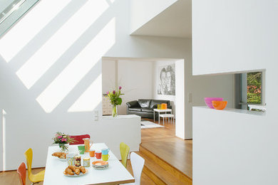Offenes, Mittelgroßes Modernes Esszimmer ohne Kamin mit weißer Wandfarbe, braunem Holzboden und braunem Boden in Köln
