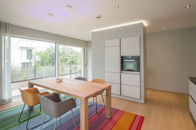 Contemporary kitchen/dining room in Nuremberg with light hardwood flooring, grey walls and brown floors.