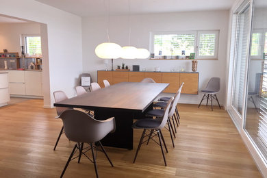 Стильный дизайн: большая гостиная-столовая в современном стиле с белыми стенами, светлым паркетным полом и коричневым полом без камина - последний тренд