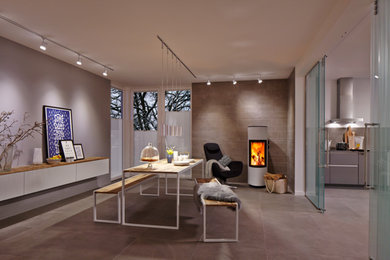 Modernes Esszimmer mit grauer Wandfarbe, Keramikboden, Kaminofen, Kaminumrandung aus Metall und beigem Boden in Essen