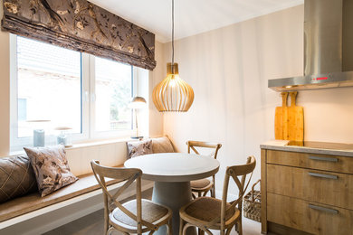 Kleine Landhaus Wohnküche mit beiger Wandfarbe, Keramikboden, Kaminofen und beigem Boden in Hamburg