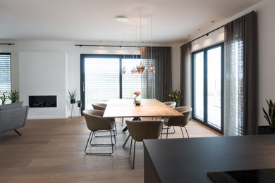 Идея дизайна: огромная гостиная-столовая в современном стиле с белыми стенами, полом из ламината и коричневым полом