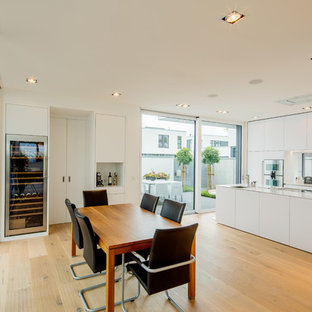 Große Moderne Wohnküche ohne Kamin mit braunem Holzboden, braunem Boden und weißer Wandfarbe in Düsseldorf