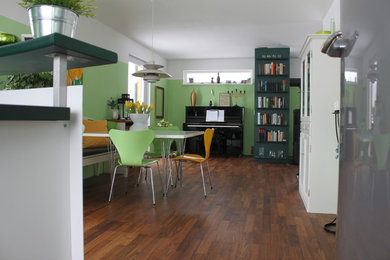 Immagine di una sala da pranzo aperta verso il soggiorno design di medie dimensioni con pareti verdi e parquet scuro