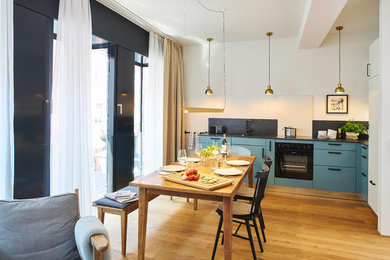 Mittelgroße Moderne Wohnküche mit weißer Wandfarbe, braunem Holzboden und beigem Boden in Sonstige
