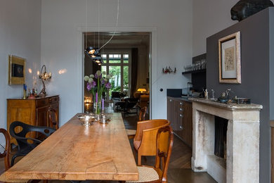 Offenes, Mittelgroßes Shabby-Style Esszimmer mit weißer Wandfarbe, braunem Holzboden, Kamin, Kaminumrandung aus Beton und braunem Boden in Hamburg