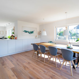 Große Nordische Wohnküche ohne Kamin mit weißer Wandfarbe, braunem Holzboden und braunem Boden in Nürnberg