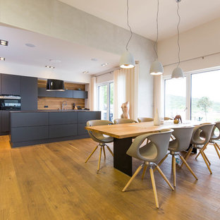 Große Moderne Wohnküche ohne Kamin mit weißer Wandfarbe, braunem Holzboden und braunem Boden in Nürnberg