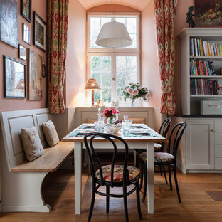 Foto på en stor lantlig matplats med öppen planlösning, med rosa väggar och mellanmörkt trägolv