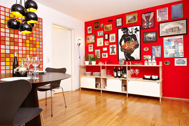Aménagement d'une salle à manger ouverte sur la cuisine contemporaine de taille moyenne avec un mur rouge et un sol en bois brun.