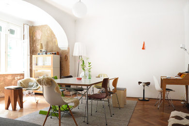 Exemple d'une salle à manger ouverte sur le salon éclectique de taille moyenne avec un sol en bois brun et un mur blanc.