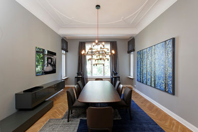 Imagen de comedor contemporáneo de tamaño medio cerrado con paredes grises, suelo marrón y suelo de madera clara