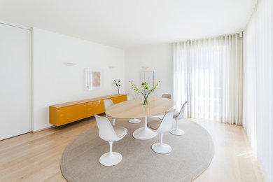 Réalisation d'une salle à manger minimaliste fermée et de taille moyenne avec un mur blanc, parquet clair, aucune cheminée et un sol beige.