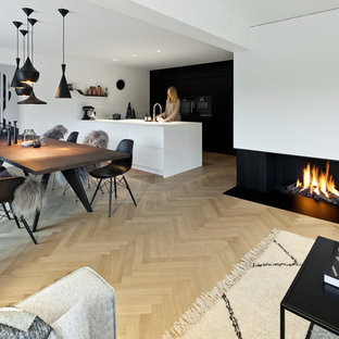Modern inredning av ett stort kök med matplats, med vita väggar, ljust trägolv, en bred öppen spis, en spiselkrans i gips och beiget golv