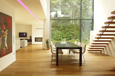 Exemple d'une très grande salle à manger ouverte sur le salon tendance avec un mur blanc et un sol en bois brun.