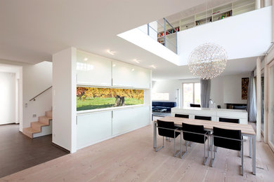 Réalisation d'une grande salle à manger ouverte sur le salon design avec un mur blanc et parquet clair.
