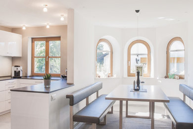 Mittelgroße Moderne Wohnküche ohne Kamin mit weißer Wandfarbe und beigem Boden in München