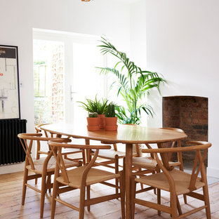 Photo of a medium sized scandinavian open plan dining room in London with white walls, medium hardwood flooring, brown floors, a standard fireplace and a brick fireplace surround.