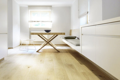Imagen de comedor de cocina minimalista grande con paredes blancas, suelo de madera clara, todas las chimeneas, marco de chimenea de yeso y suelo marrón