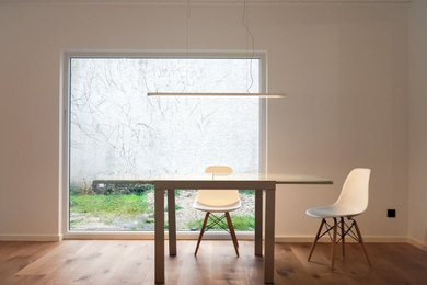 Offenes Modernes Esszimmer mit weißer Wandfarbe, braunem Holzboden, Kaminofen und braunem Boden in Dortmund