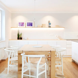 Nordische Wohnküche ohne Kamin mit weißer Wandfarbe, braunem Holzboden und braunem Boden in München